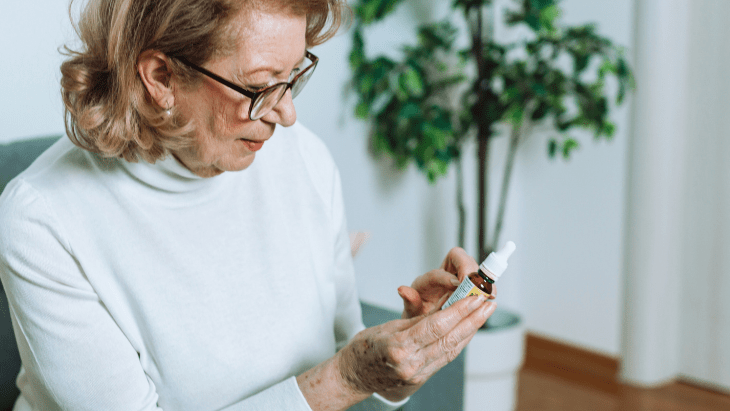 A senior woman reads the label on a cannabis CBD bottle